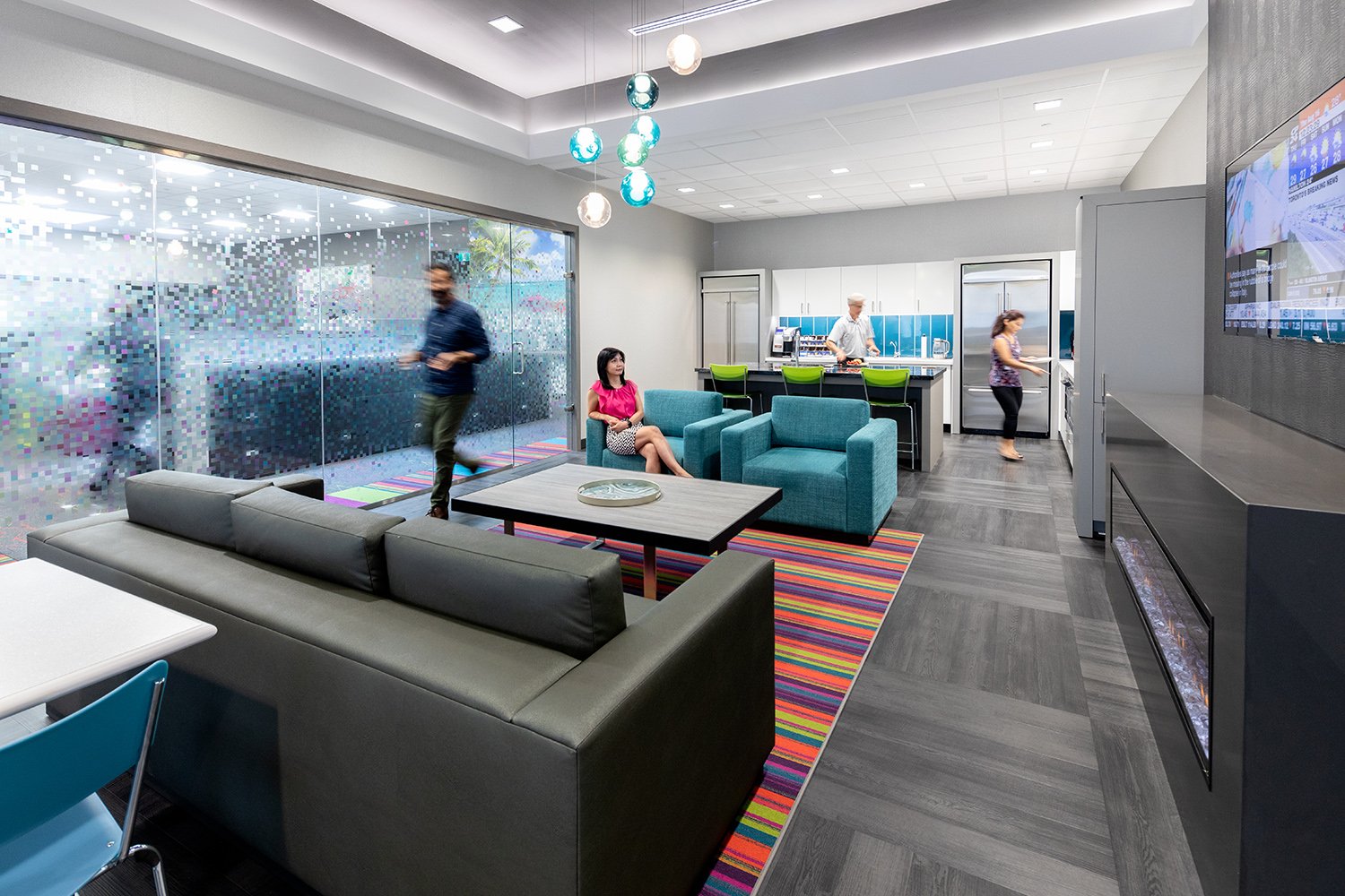 Modern Acorn Developments office lounge with colourful seating, a kitchen area and people gathering